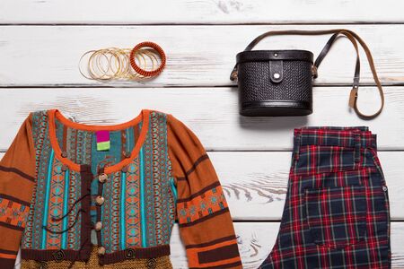 Embroidered top and bracelets. Black bag and colorful top. Bracelet set on white table. Stylish spring clothes on display.の写真素材