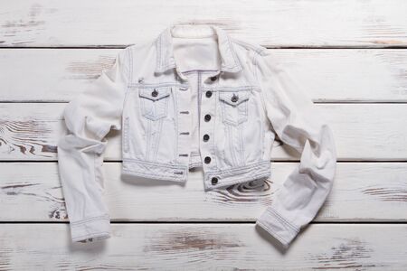 Short white jacket. Short jacket on wooden background. Lady's trendy spring outerwear. Special offer in outlet store.の写真素材