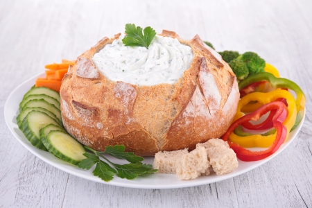 bread bowl with cheese spread and vegetablesの写真素材