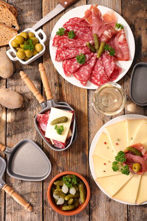 table with raclette cheese, meat and potatoの写真素材