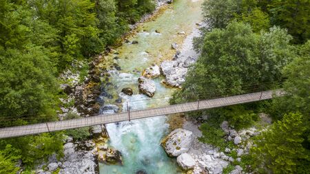 wooden suspension bridge with river and forestの写真素材