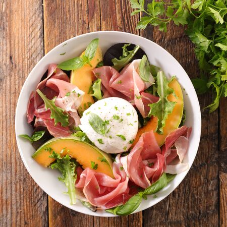 bowl with lettuce, cantaloupe melon, prosciutto ham and mozzarellaの写真素材
