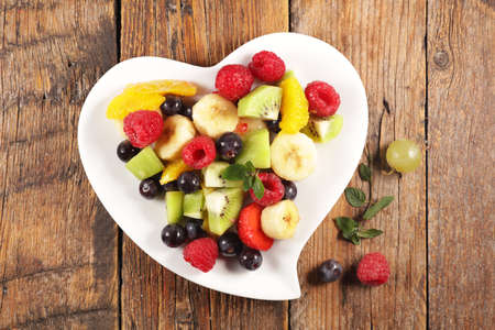 fresh mixed fruit salad in heart shape plateの写真素材