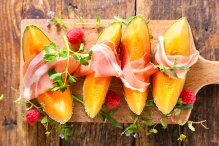 melon slices with prosciutto ham and herbsの写真素材
