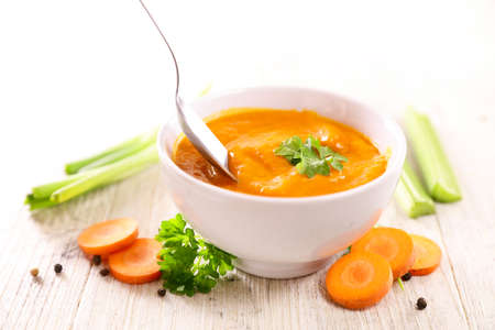 bowl of carrot soup and spoonの写真素材