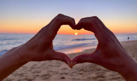 hand heart shape at sunset