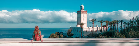Woman tourist looking at lighthouse of Cap Spartel, Tangier, Morocco in Africa
