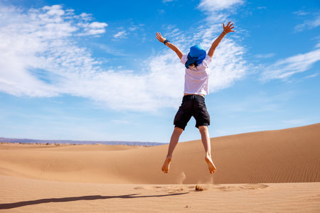 Children jumping in sand dunes in the Sahara desertの写真素材