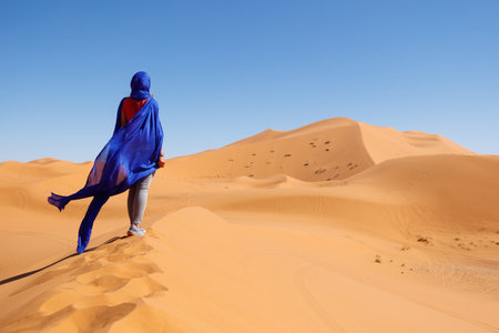 Woman wearing blue turban looking at sahara desert in Moroccoの写真素材