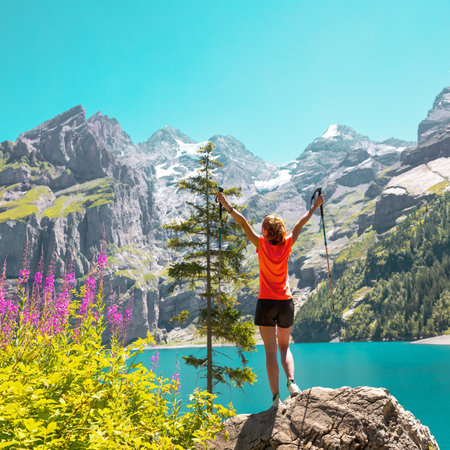 Happy hiker woman standing on rock looking at majestic view of mountain and lake- Switzerlandの写真素材