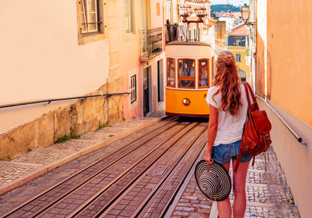 Traditional yellow trams, funicular on a street in Lisbon with woman tourist travel in Portugalの写真素材