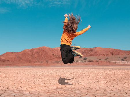 Boy jumping in desert landscape- Moroccoの写真素材