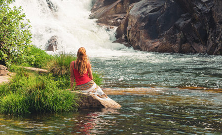 Woman sitting enjoying amazing waterfall- Galicia, Spainの写真素材