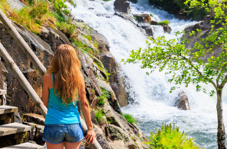 Traveler woman looking at waterfall- Galicia, Spainの写真素材