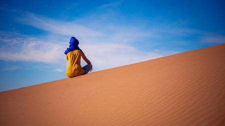 Woman sitting on sand dune in Sahara desert- travel, adventure, wanderlust conceptの写真素材