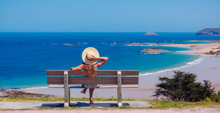 Woman sitting on a bench looking at Atlantic Ocean - vacation, travel destination, relaxing, summer holiday (Brittany in France)の写真素材