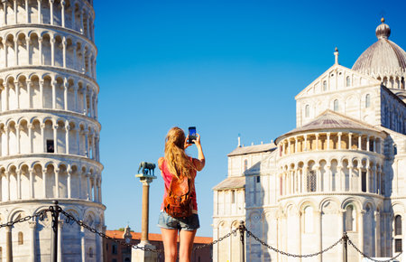 Woman traveling in Italy and taking photography with smartphone- Pisa tower, Cathedral- tourism, travel in Europeの写真素材