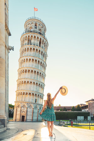 Woman with hat and blue dress enjoying Leaning Tower in Pisa in Italy- tour tourism, travel, vacation in Europeの写真素材