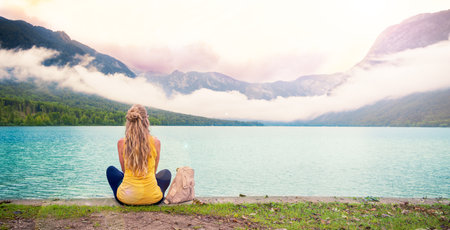 Woman sitting and looking at beautiful mountain lake landscape- relax, vacation, serene people...