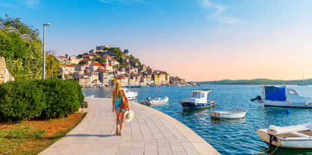 one person walking along the sea with boats, town of Sibenik- travel, tourism in Croatia- Europaの写真素材