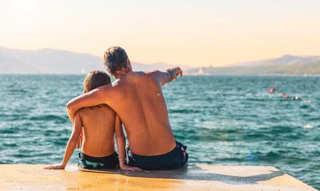 Father and son relaxing on pier enjoying beautiful sea- travel, vacation, summer holidayの写真素材