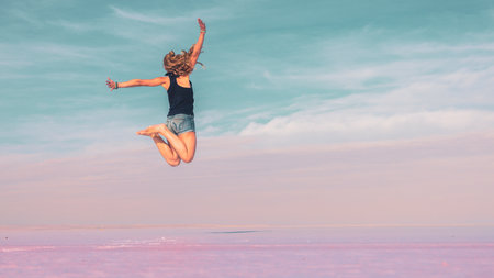 Carefree woman jumping on pink salt lake - active, wellness, healthy lifestyle conceptの写真素材