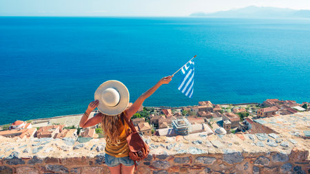 Young female with Greek flag enjoys city and mediterranean sea- Travel destination, summer holiday concept in Greece, Peloponneseの写真素材