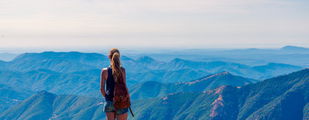 Hiker woman standing on peak enjoying panoramic view of mountain range (Mont Aigoual in France)