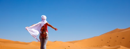 Rear view of young woman with white waving textile in the sahara desert.の写真素材