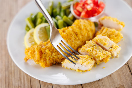 fried breaded chicken fillet with bean and tomatoesの写真素材