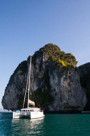 Sail is floating on blue sea with a huge granite rockの写真素材