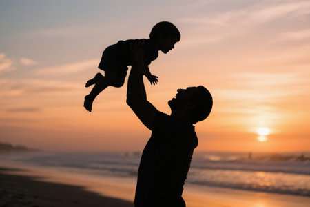 Father and son are playing on the beach at sunset. Concept of a friendly family.の素材