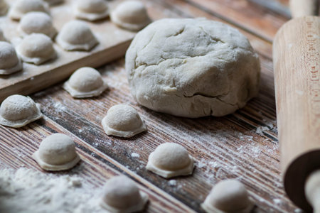 Cooking dumplings. On the table are dumplings on a wooden board, next to a rolling pin of dough.の写真素材