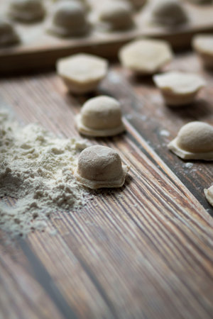 Cooking dumplings. On the table are dumplings on a wooden board, next to a rolling pin of dough.の写真素材