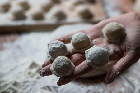 Cooking dumplings. On the table are dumplings on a wooden board, next to a rolling pin of dough.の写真素材