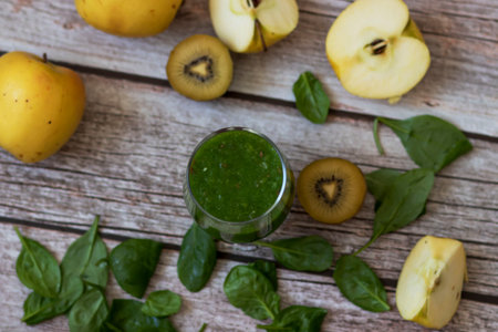 A glass of kiwi, spinach and apple smoothie. Health drink. Apples, flax seeds, spinach, kiwi, bananas lie nearby.の写真素材