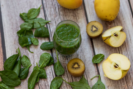 A glass of kiwi, spinach and apple smoothie. Health drink. Apples, flax seeds, spinach, kiwi, bananas lie nearby.の写真素材