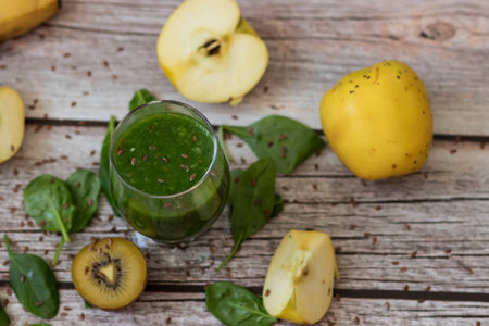 A glass of kiwi, spinach and apple smoothie. Health drink. Apples, flax seeds, spinach, kiwi, bananas lie nearby.の写真素材