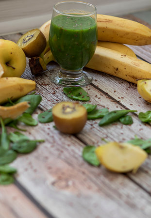 A glass of kiwi, spinach and apple smoothie. Health drink. Apples, flax seeds, spinach, kiwi, bananas lie nearby.の写真素材