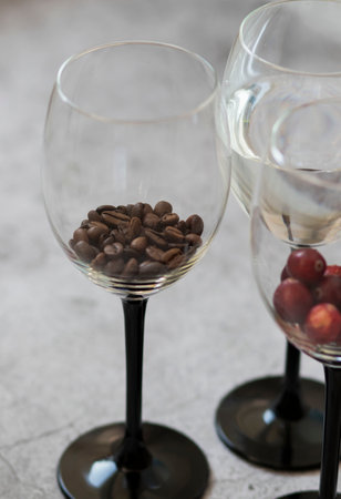 Wine glasses. They stand or lie on a gray background. They are filled with wine and coffee, cranberries.の写真素材