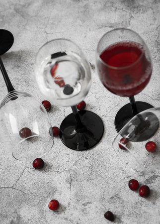 Wine glasses. They stand or lie on a gray background. They are filled with wine and coffee, cranberries.の写真素材