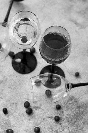 Wine glasses. They stand or lie on a gray background. They are filled with wine and coffee, cranberries.の写真素材