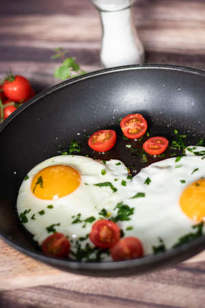 Fried eggs in a frying pan. Stand on a tree board on the table