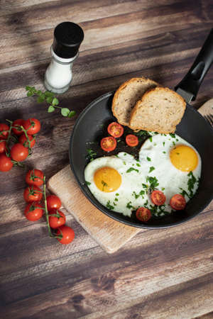 Fried eggs in a frying pan. Stand on a tree board on the tableの写真素材