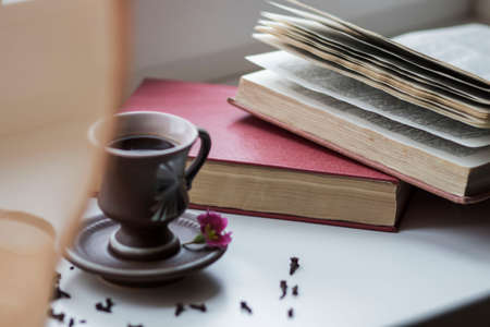 There is a beautiful coffee cup by the window. And there are books nearbyの写真素材