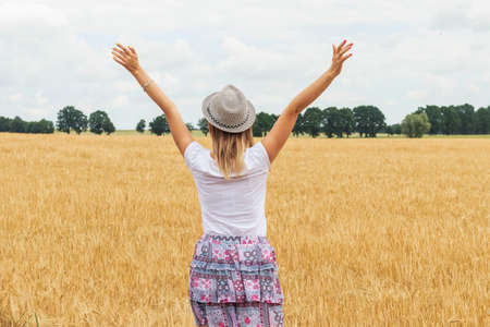 A young girl walking among a wheat fieldの写真素材