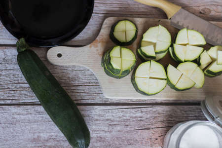 cutting zucchini with a knife on a wooden cutting boardの写真素材