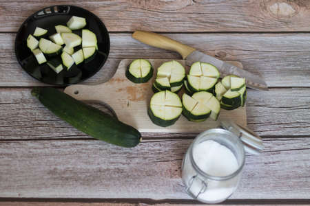 cutting zucchini with a knife on a wooden cutting boardの写真素材