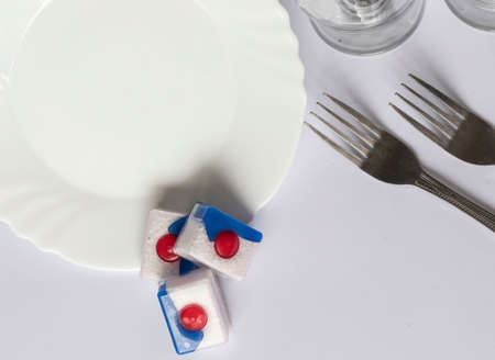 Dishwasher tablets, on white background with utensils