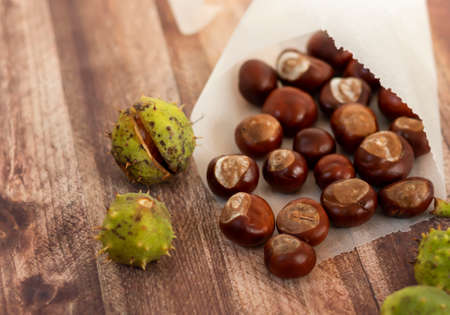 Chestnuts on a wooden table, in a paper bagの写真素材